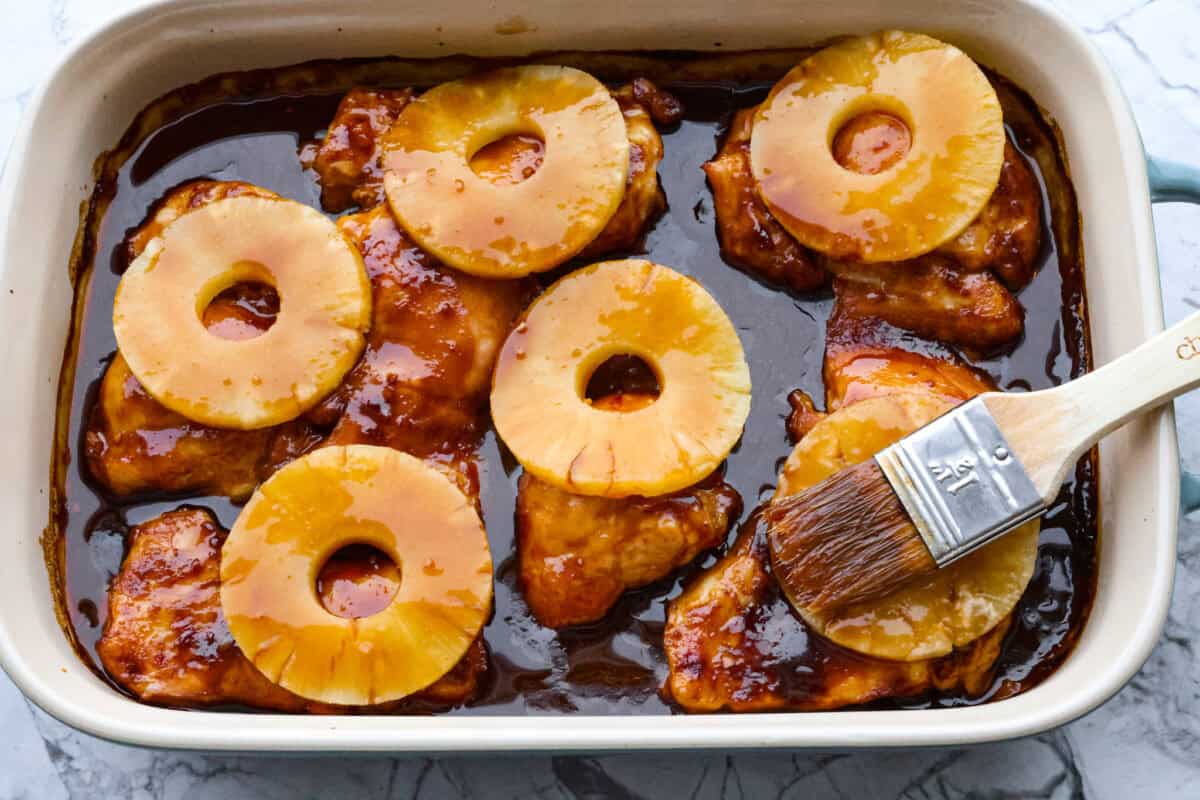 Fourth photo of the pineapple placed on top of the chicken and the sauce basting on top.