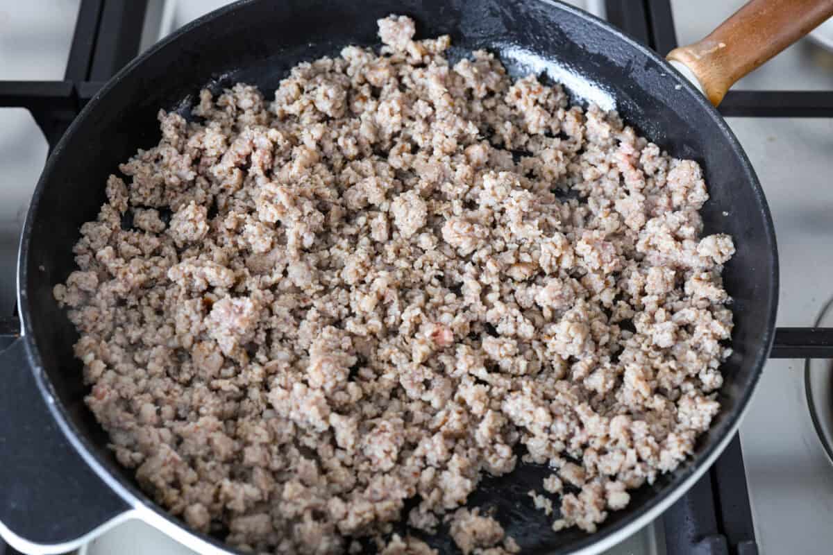 Overhead shot of sausage being cooked in a pan on the stovetop. 