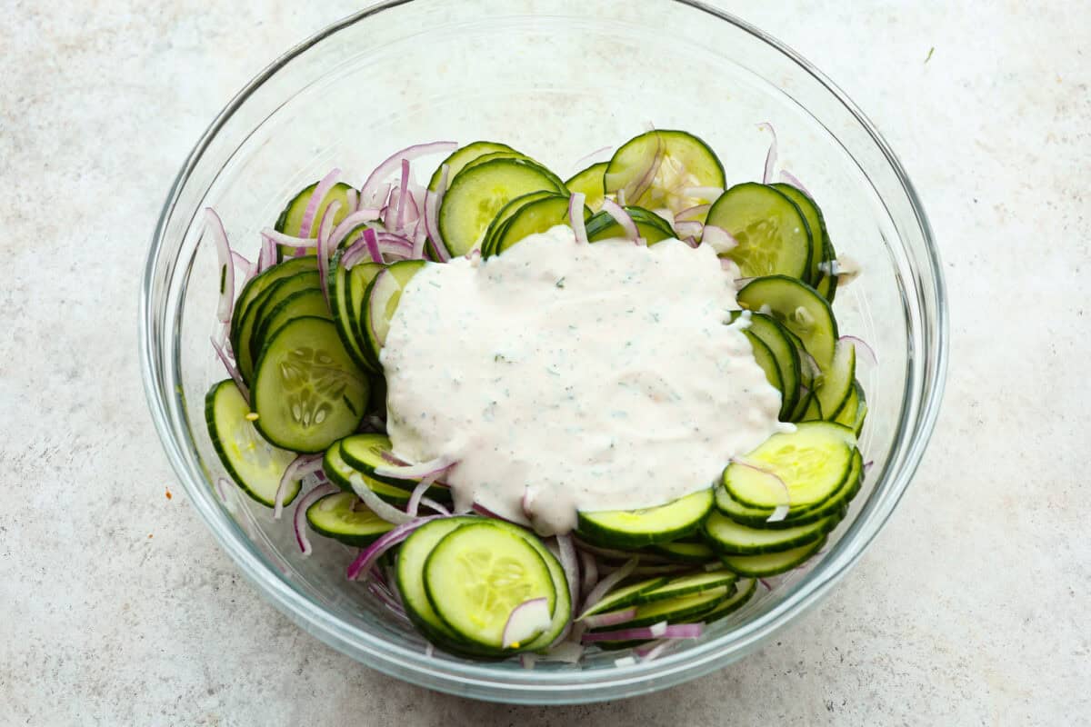 Dressing poured over cucumbers, ready to combine. 