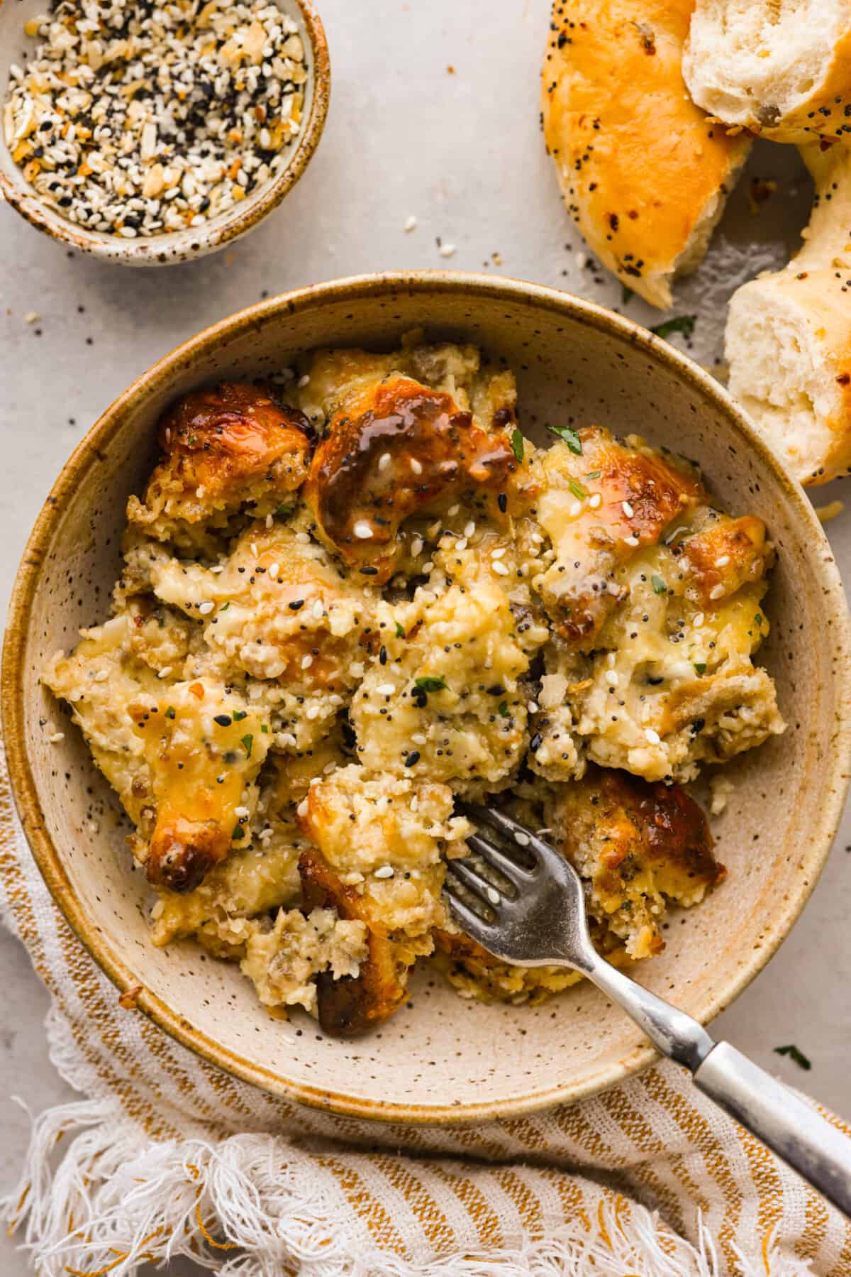 Top close view of everything bagel casserole in a brown bowl with a fork.