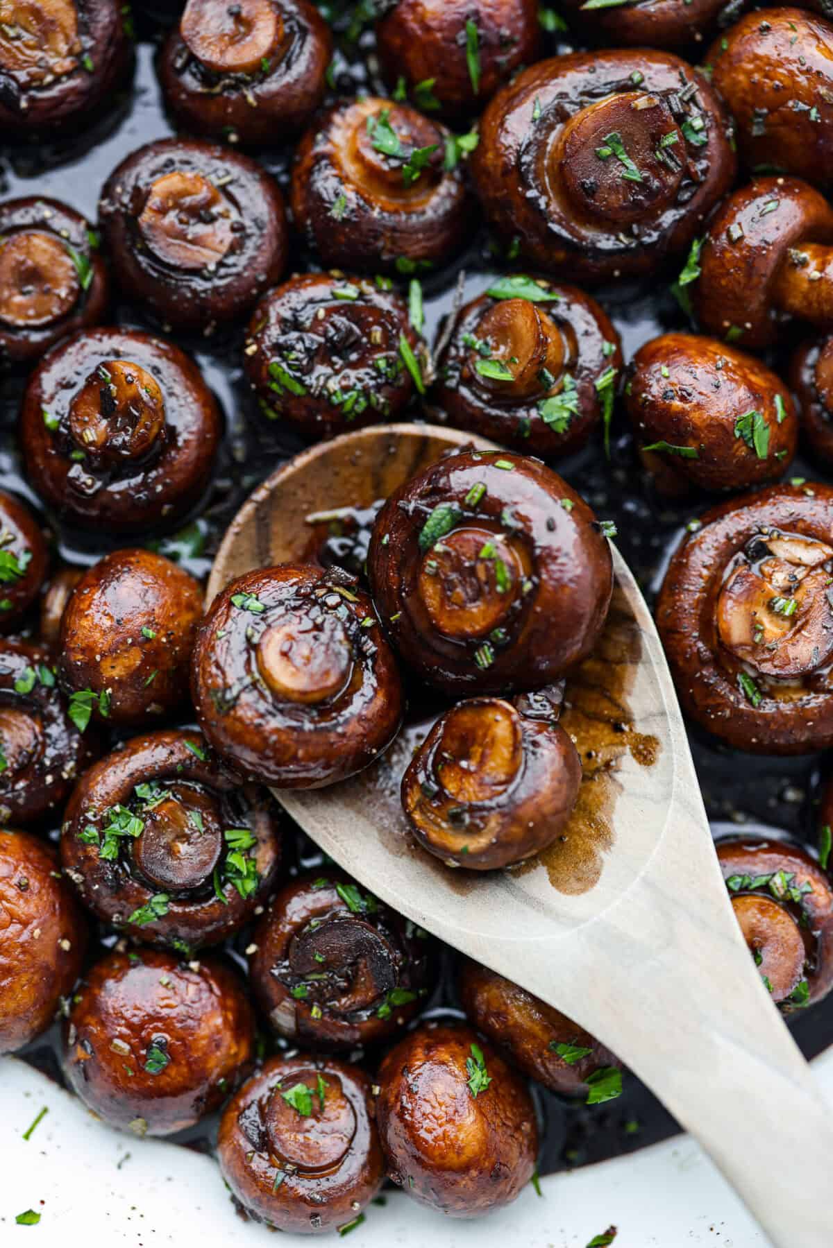 Close view of garlic balsamic mushrooms with a wood serving spoon.