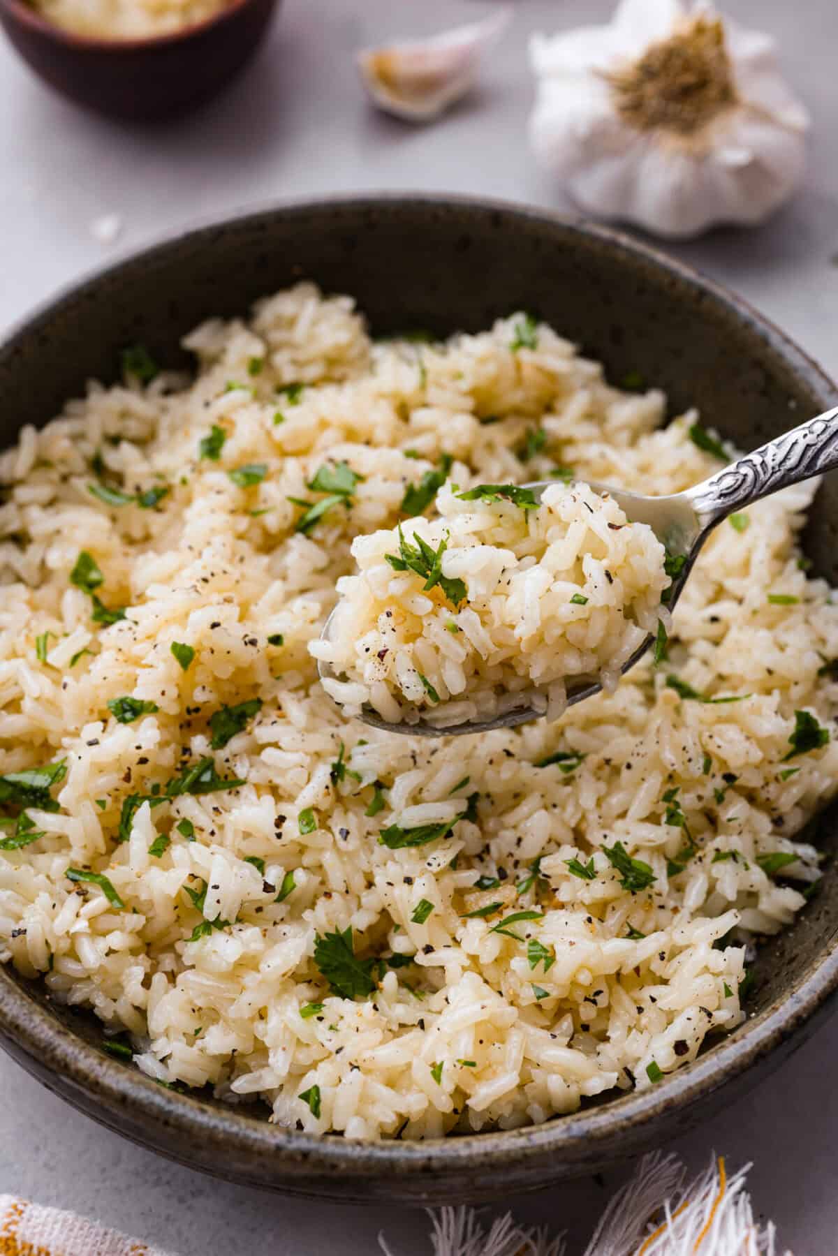 Angle shot of a plated bowl of garlic butter rice with a bite of rice on a spoon. 