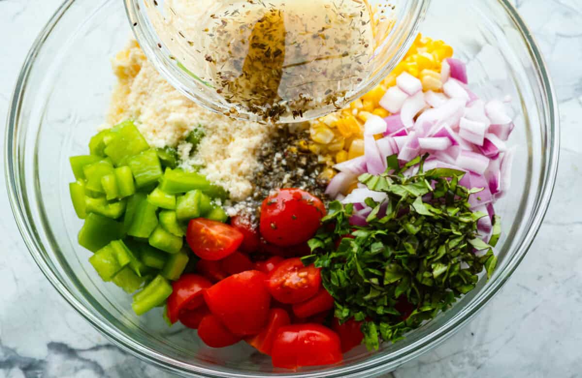 Overhead shot of dressing being poured into bowl of separated salad ingredients. 