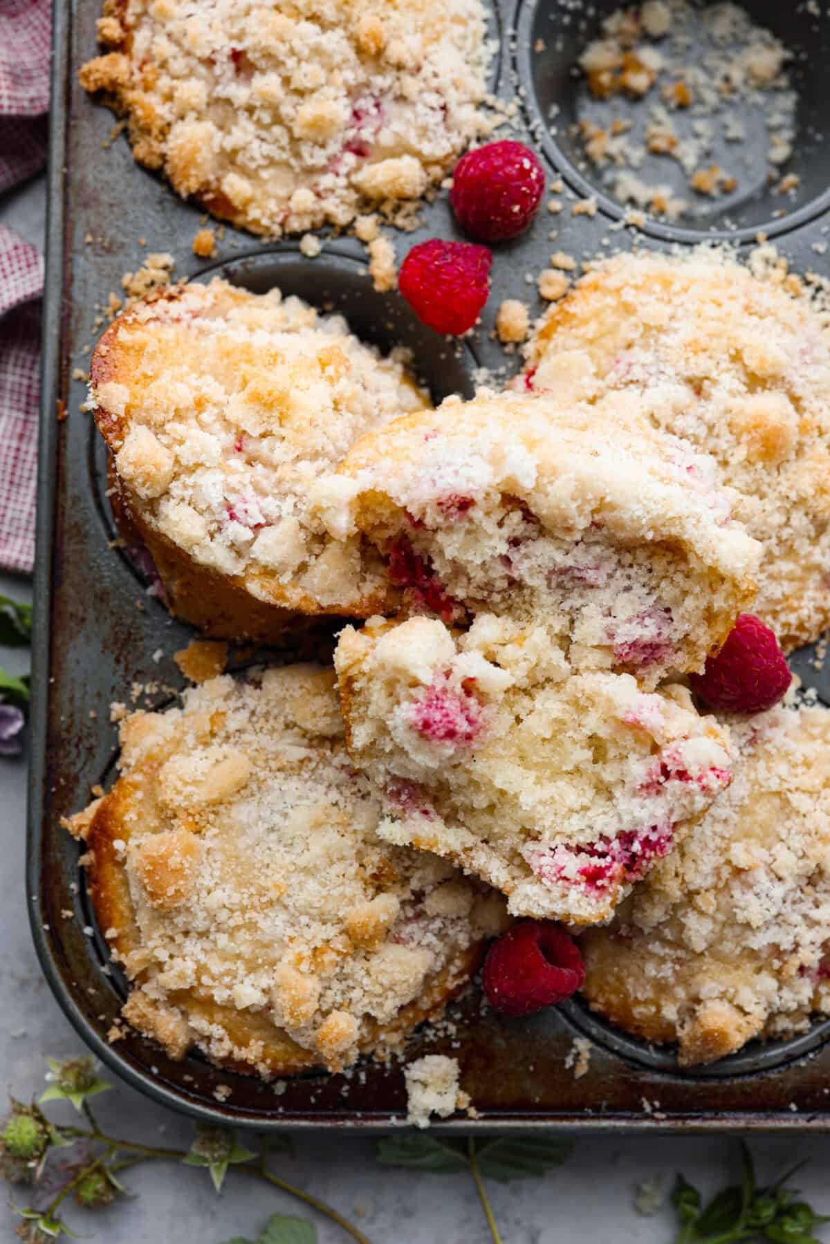 Close up shot of raspberry muffins broken up on top of muffin tin. 