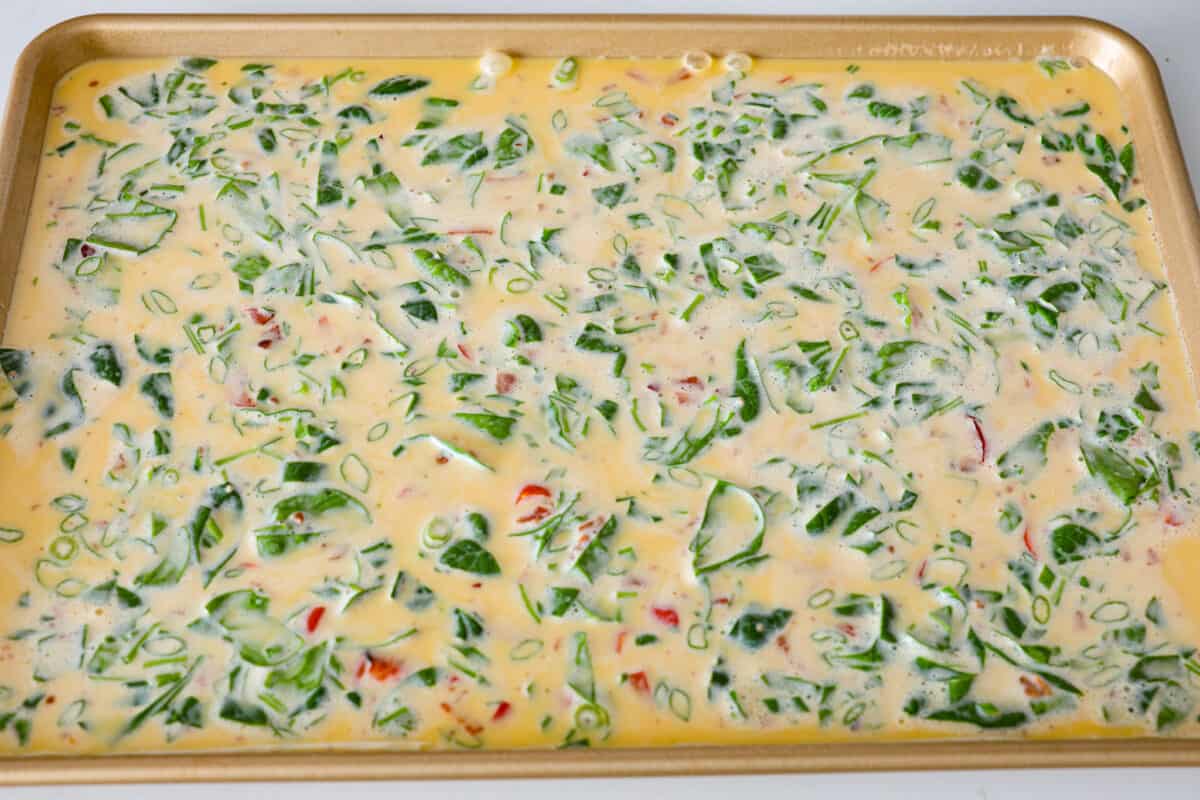 Pouring the whisked egg mixture into the sheet pan.