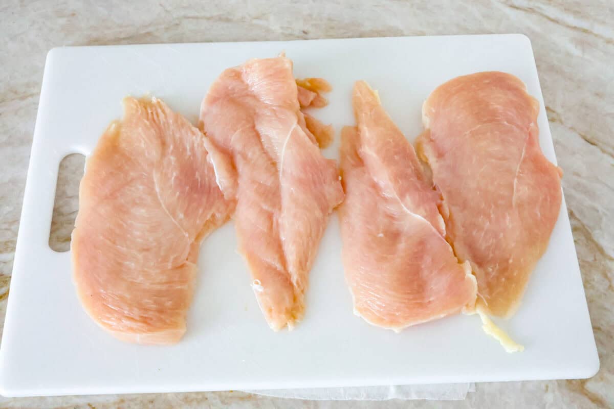 Overhead shot of tenderized chicken on cutting board. 