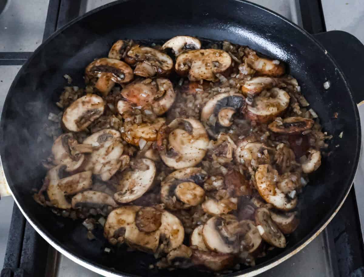 Overhead shot of mushrooms being sautéed in skillet. 