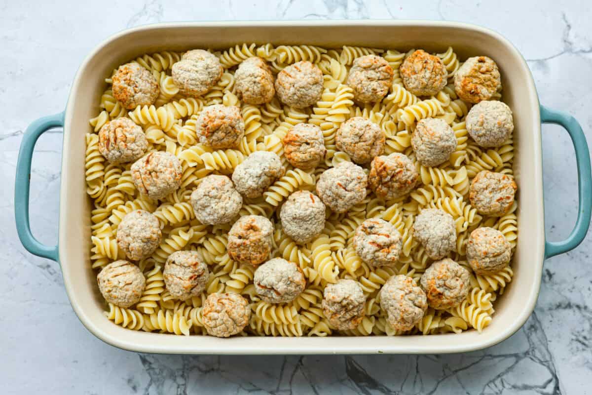 Overhead shot of casserole dish with pasta on the bottom with meatballs spaced out on top. 