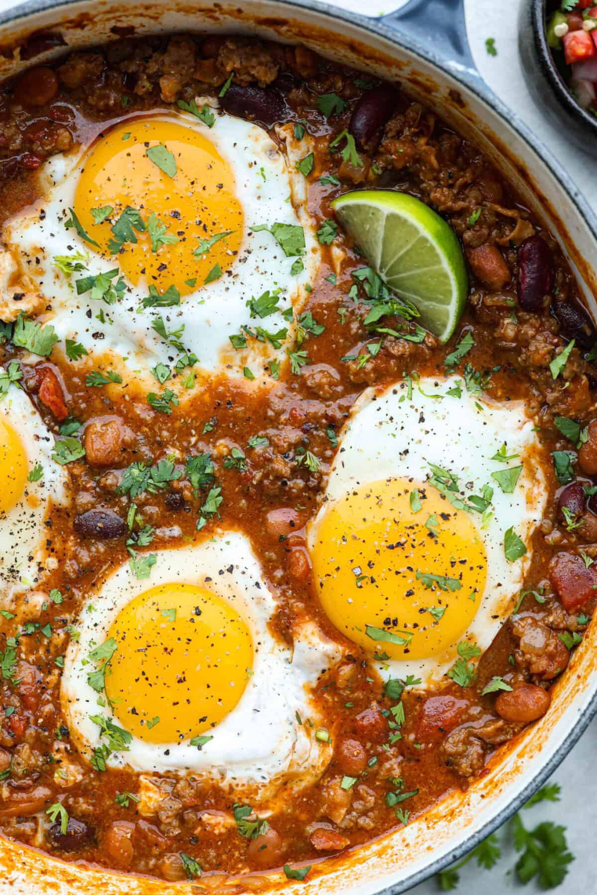 Overhead shot of a pot of breakfast chili with fried eggs on top. 