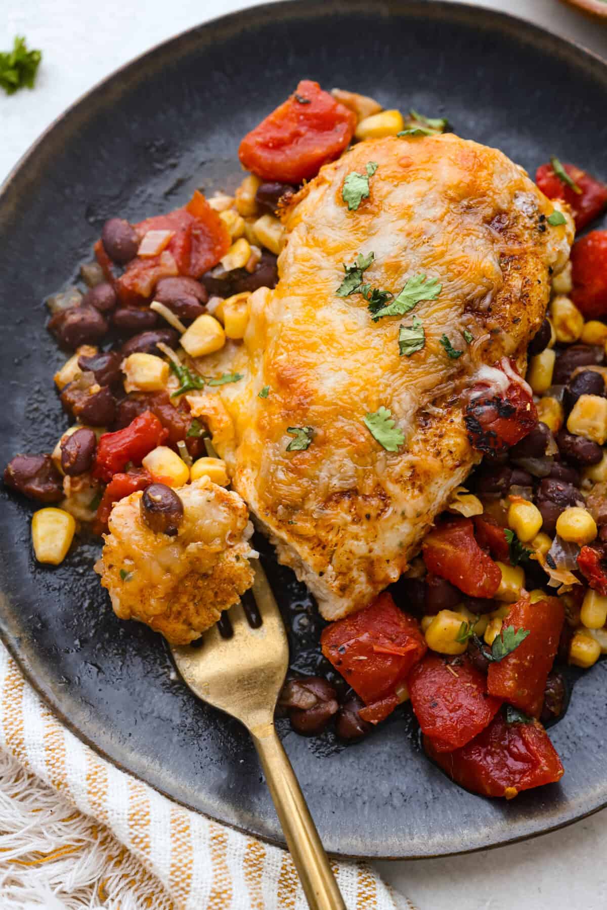 Overhead shot of plated cowboy chicken with a bit on a gold fork. 