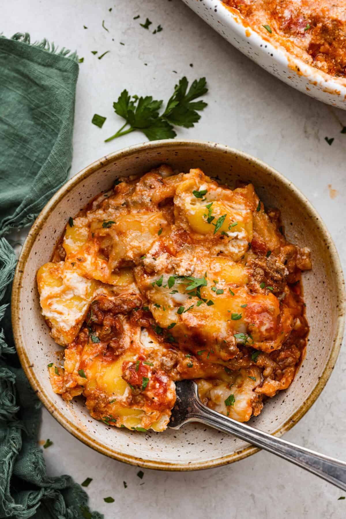 Overhead shot of a plated portion of million dollar ravioli casserole with a fork in it. 