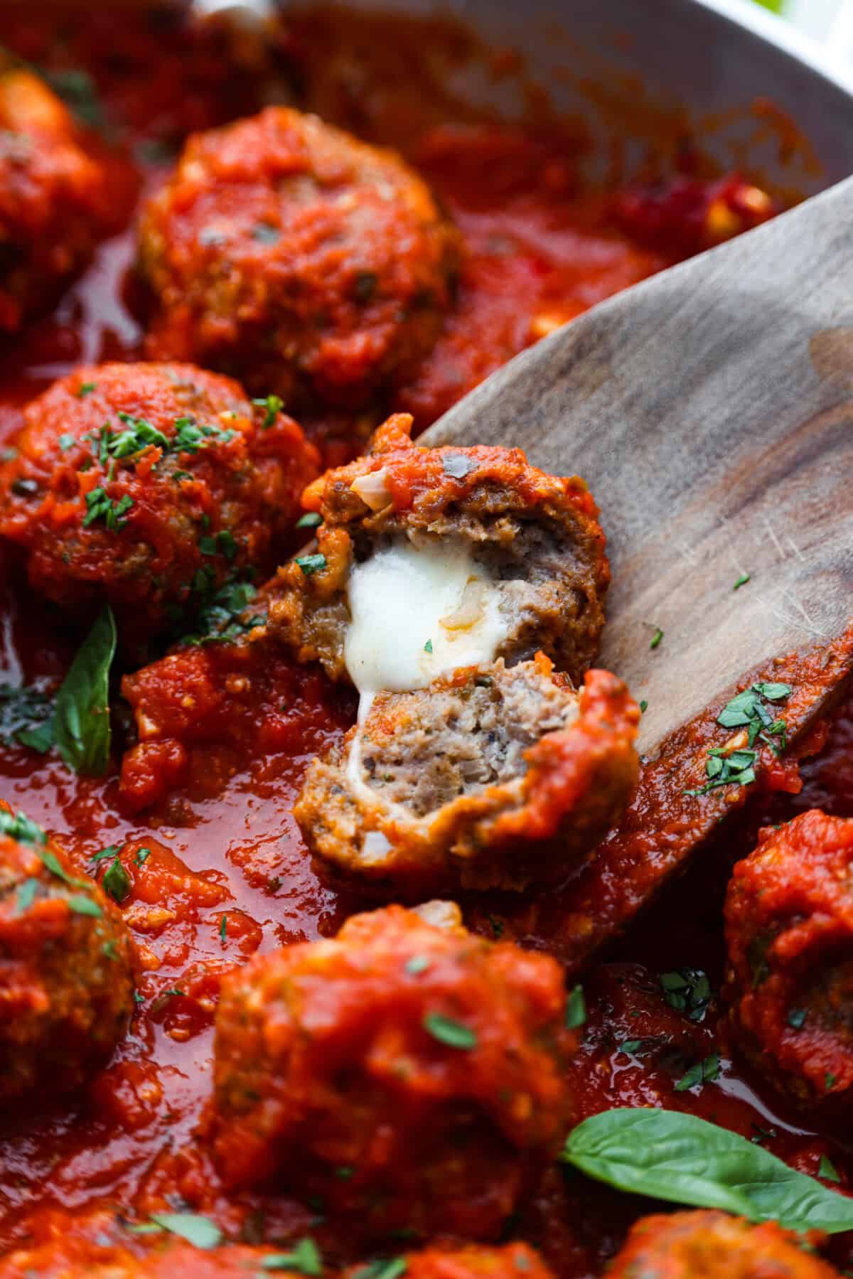 Close view of a mozzarella stuffed meatballs cut open with melted cheese.