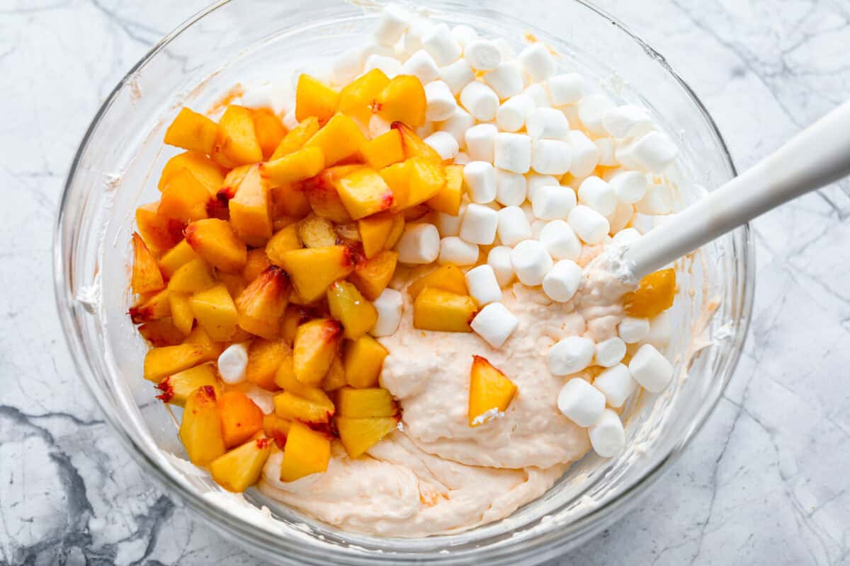 Fresh peaches and marshmallows added into the bowl for the peach fluff salad. 