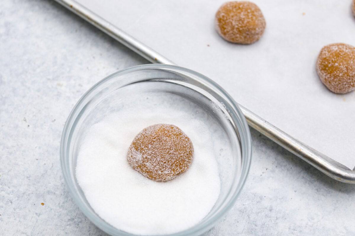 Overhead shot of dough ball being rolled in sugar. 