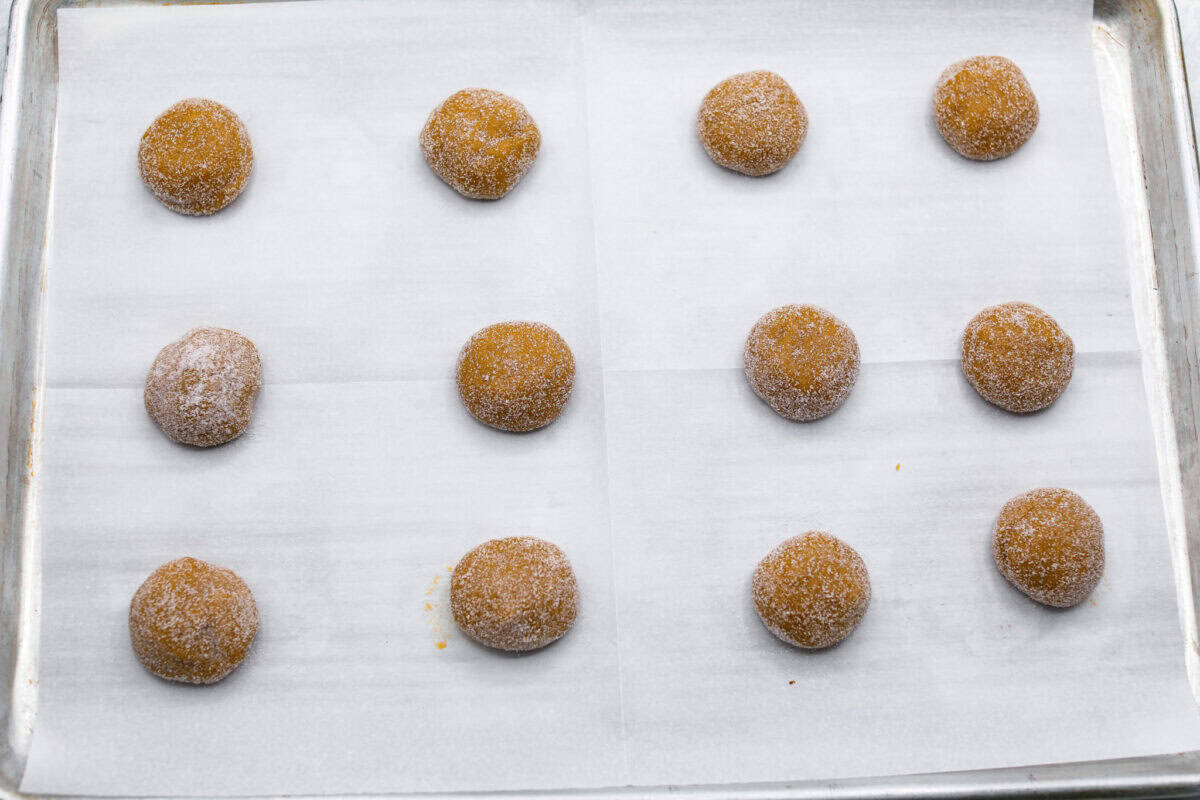 Overhead shot of cookie dough balls spread evenly on a cookie sheet. 