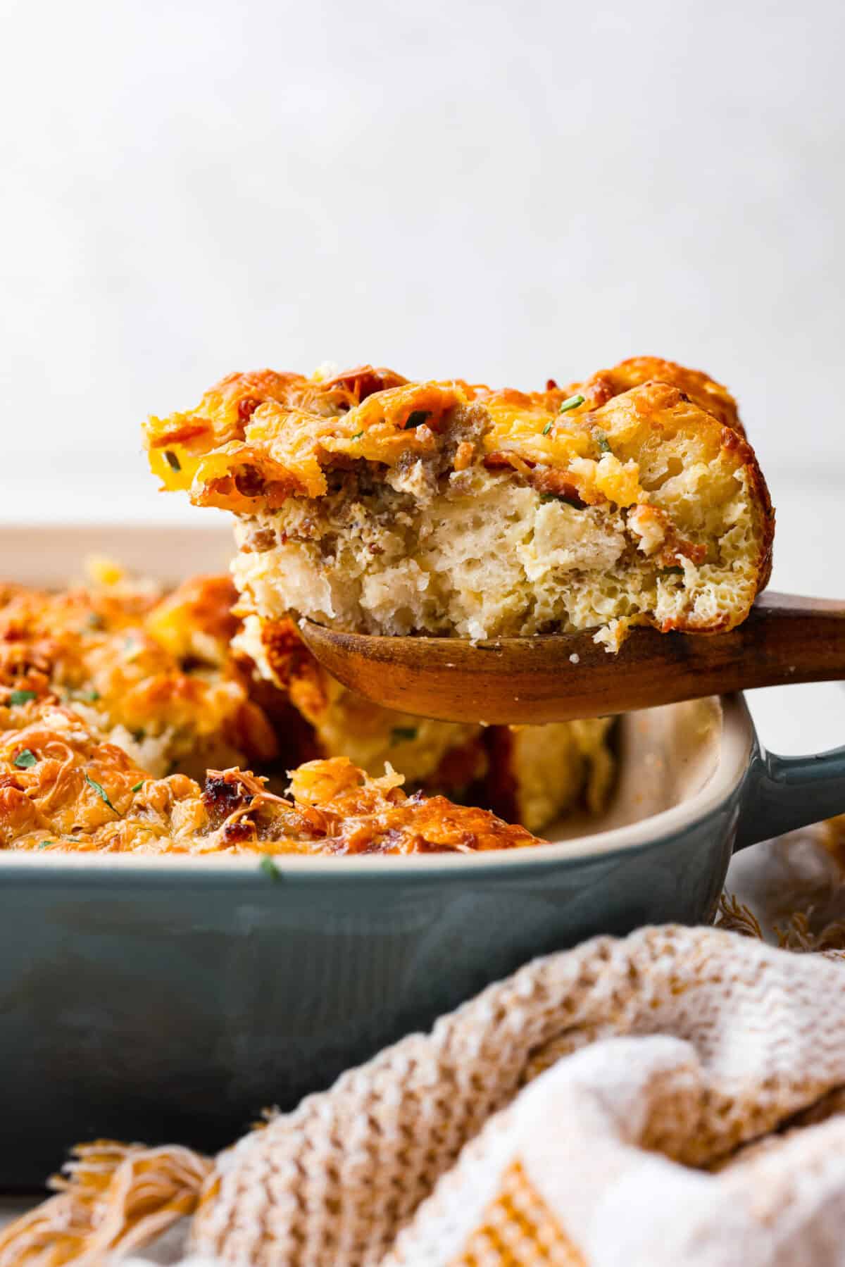 Side shot of a serving of bubble up breakfast casserole being taken out of the baking dish. 