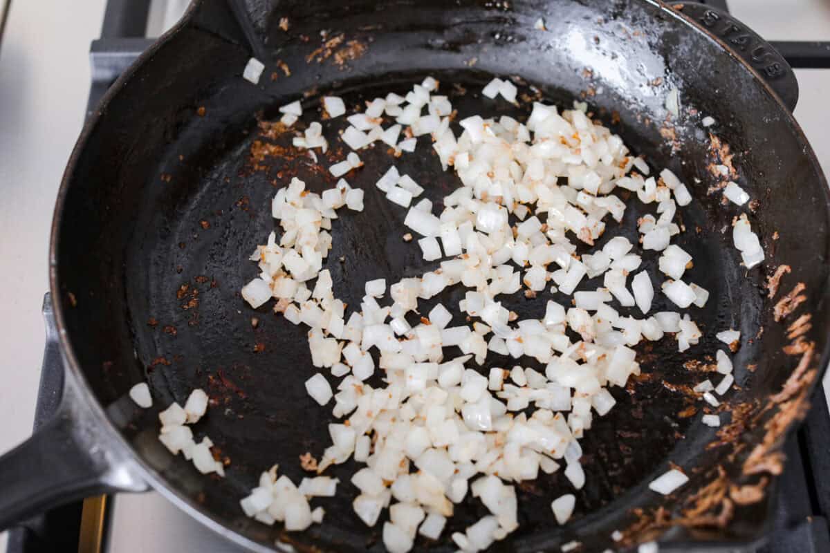 Overhead shot of onions being sautéed in a skillet. 