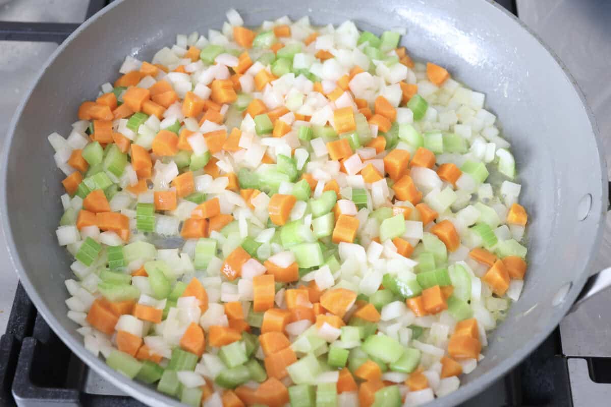 Overhead shot of veggies sautéing in a skillet. 