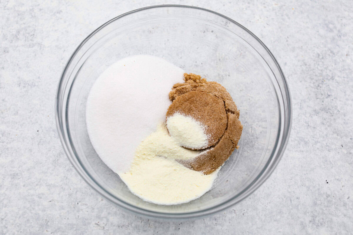 Overhead shot of sugars and milk powder in a glass bowl.