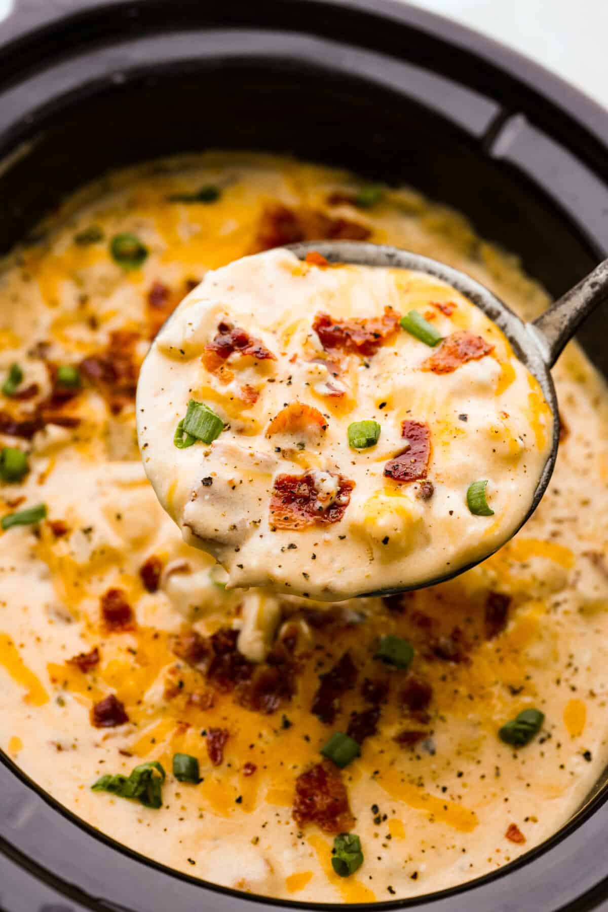 Overhead shot of a ladle filled with crock pot crack potato soup. 