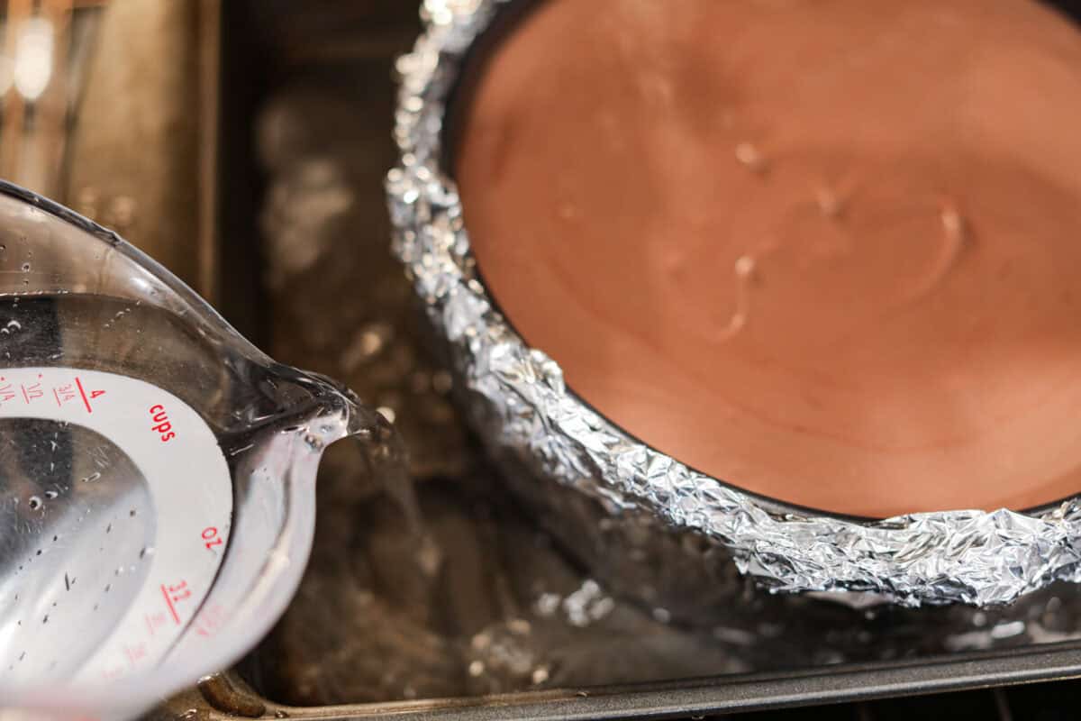 Eighth photo of the water being poured into the roasting pan to create a water bath for the German chocolate cheesecake.