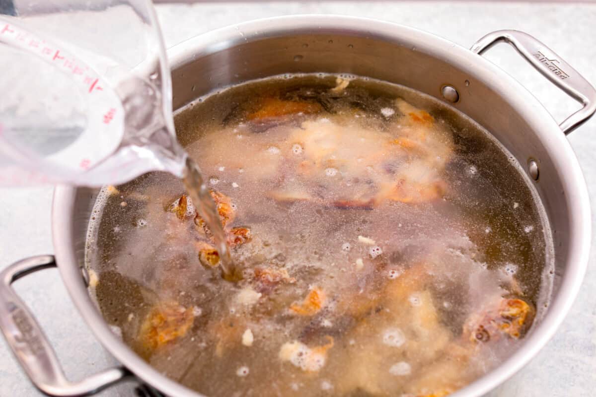 Angle shot of someone pouring water in to a pot of bones.