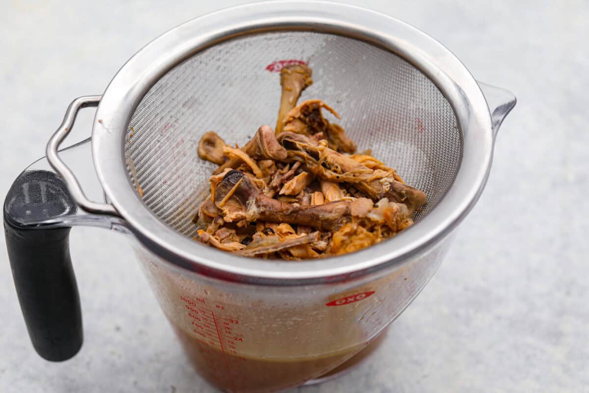 Angle shot of bones and skin being filtered out of the bone broth. 