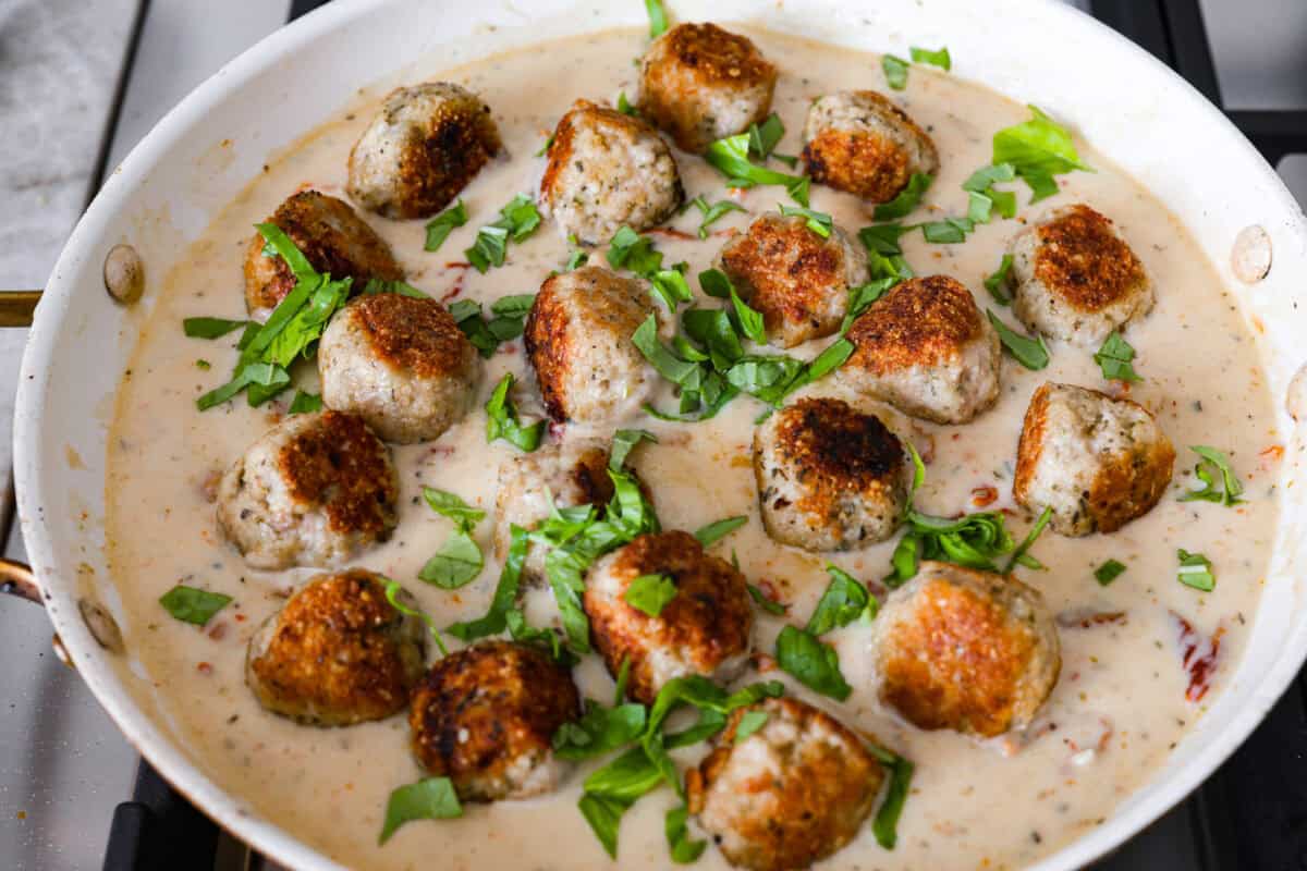 Overhead shot of meatballs and sauce in a pan with basil sprinkled over the top. 