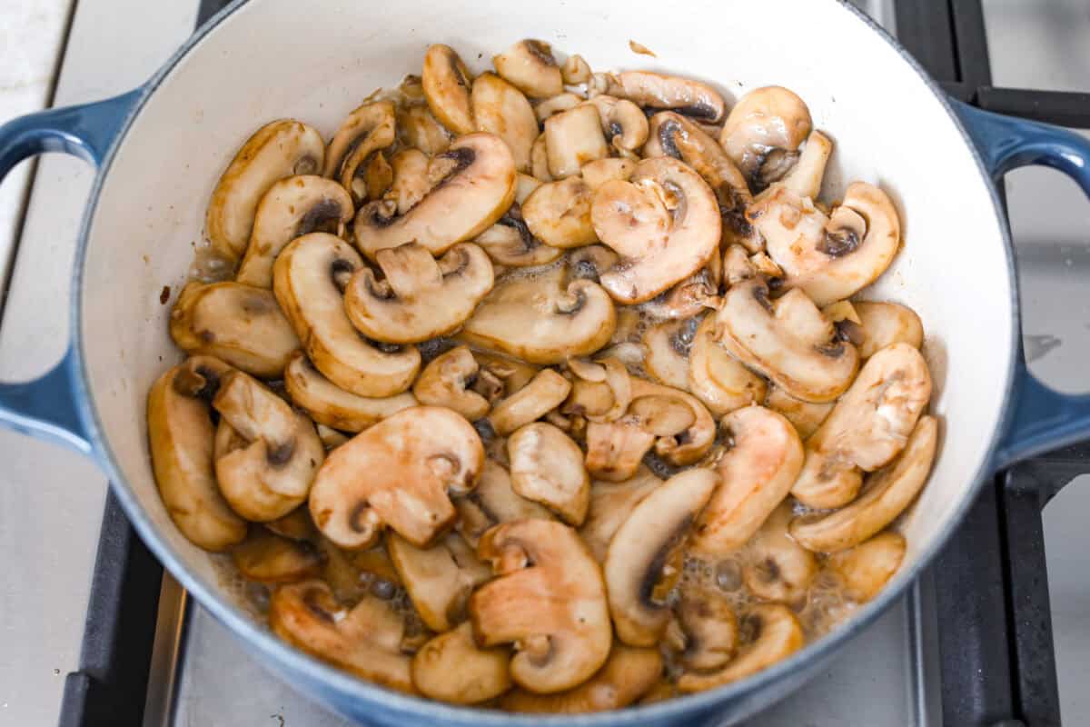 Overhead shot of mushrooms sautéing in a skillet. 