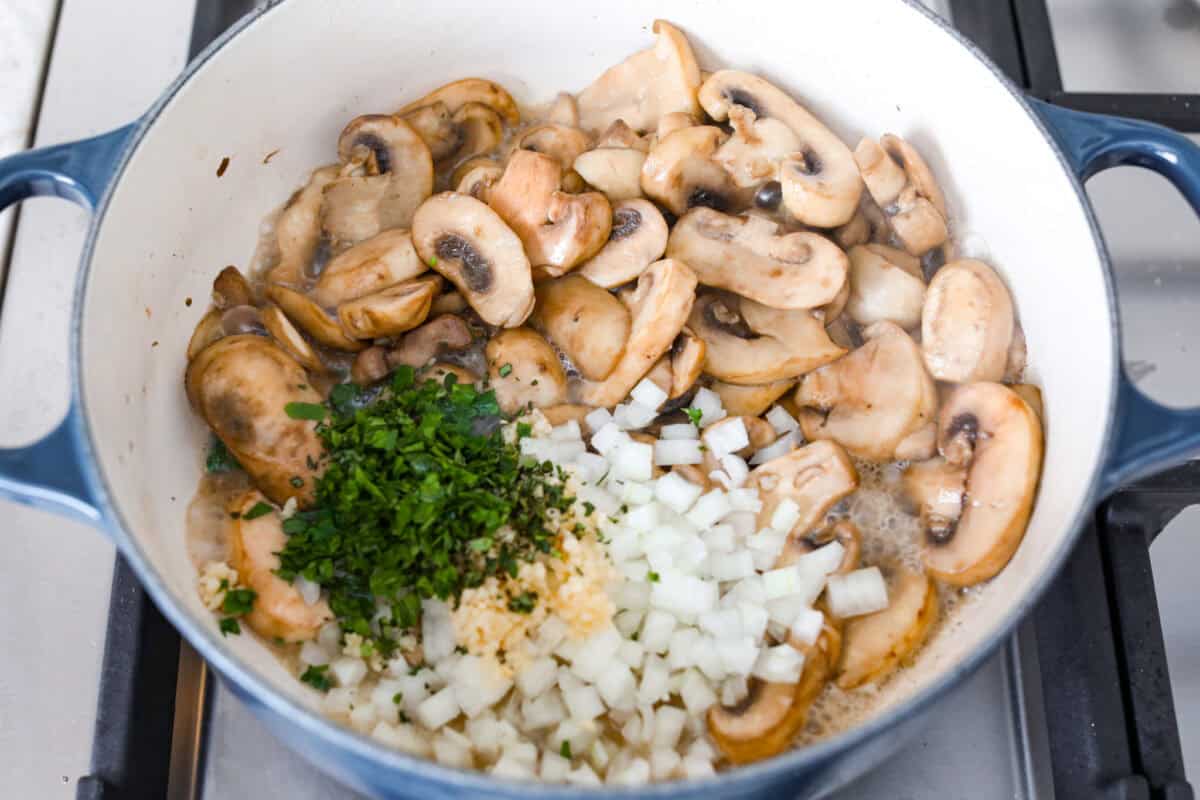 Overhead shot of sautéing mushrooms with herbs, onions and seasonings added. 