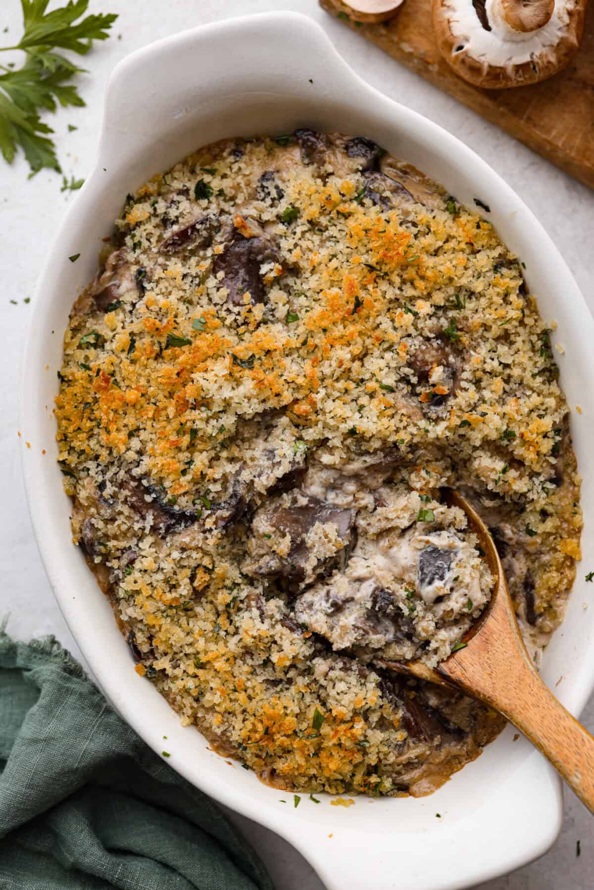 Top view of mushroom casserole in a baking dish with a wood serving spoon.