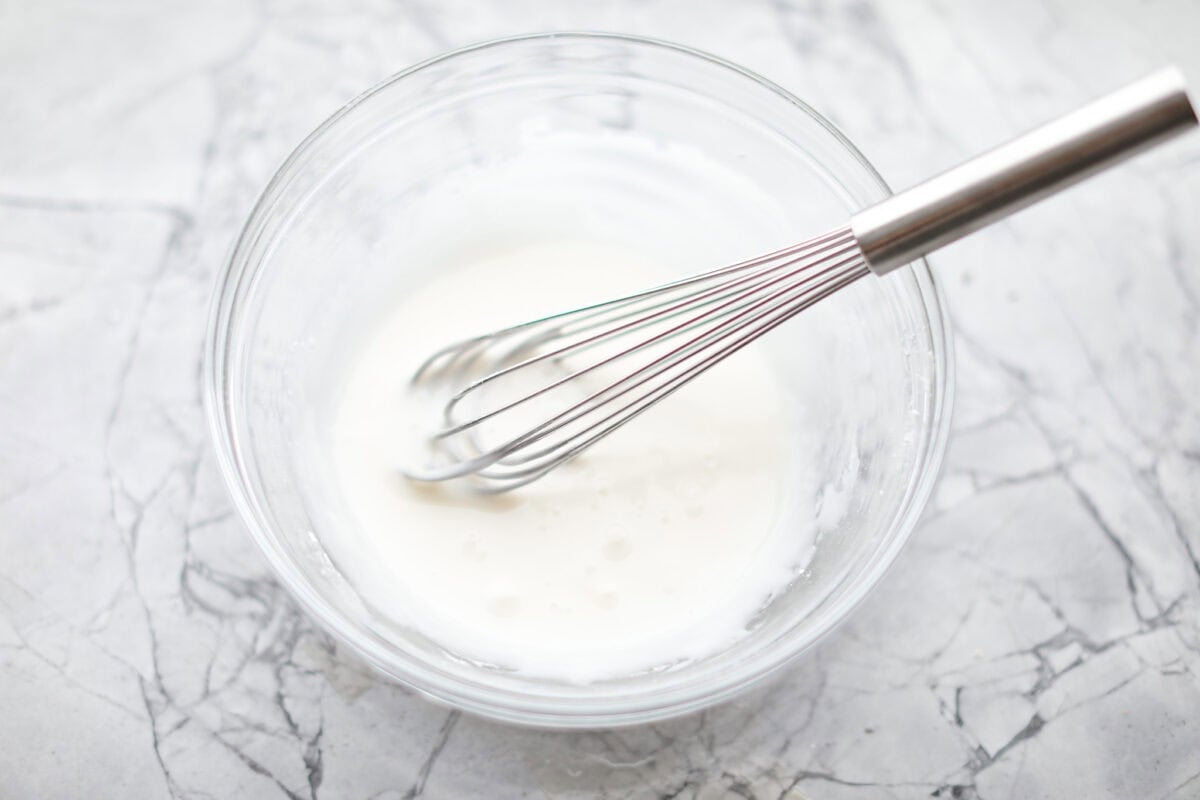 Overhead shot of biscuit cinnamon roll glaze whisked together in a bowl. 