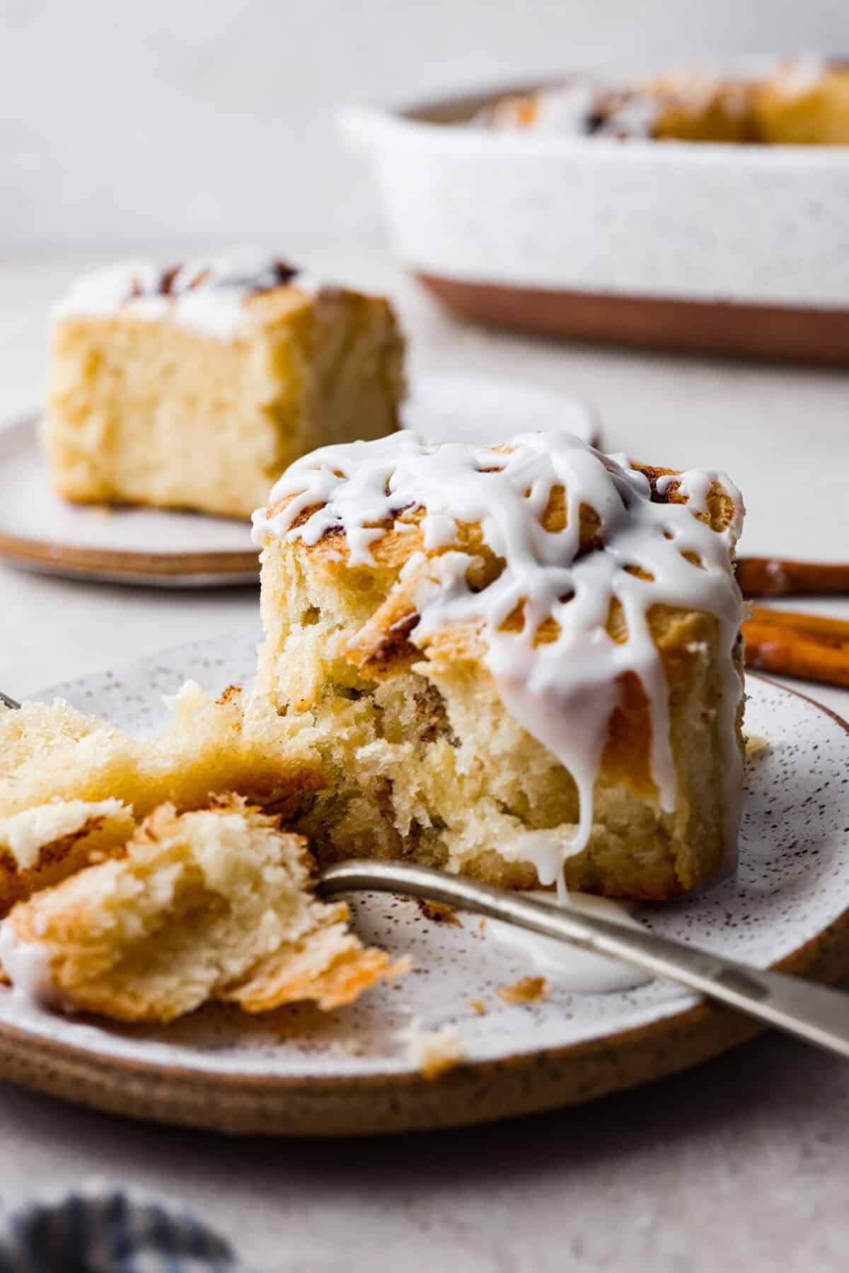 side shot of a plated biscuit cinnamon roll cut with a fork. 