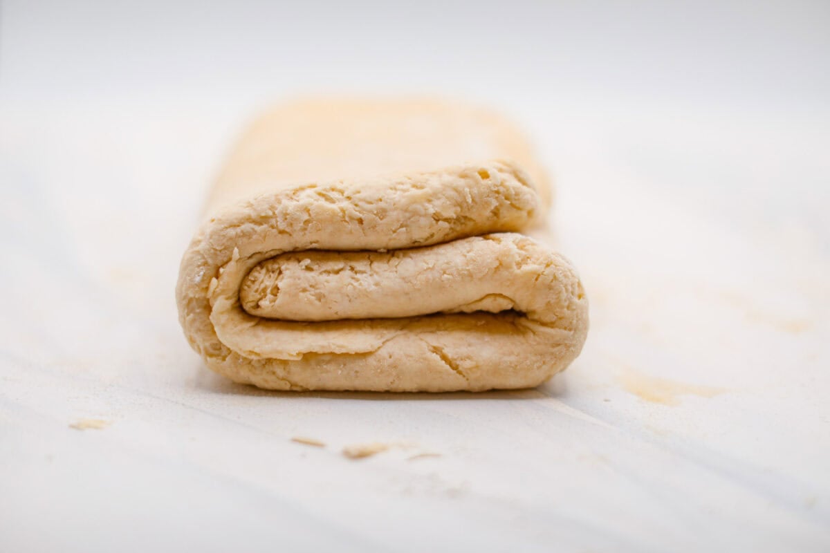 Side shot of biscuit cinnamon roll dough folded into a tri-fold.