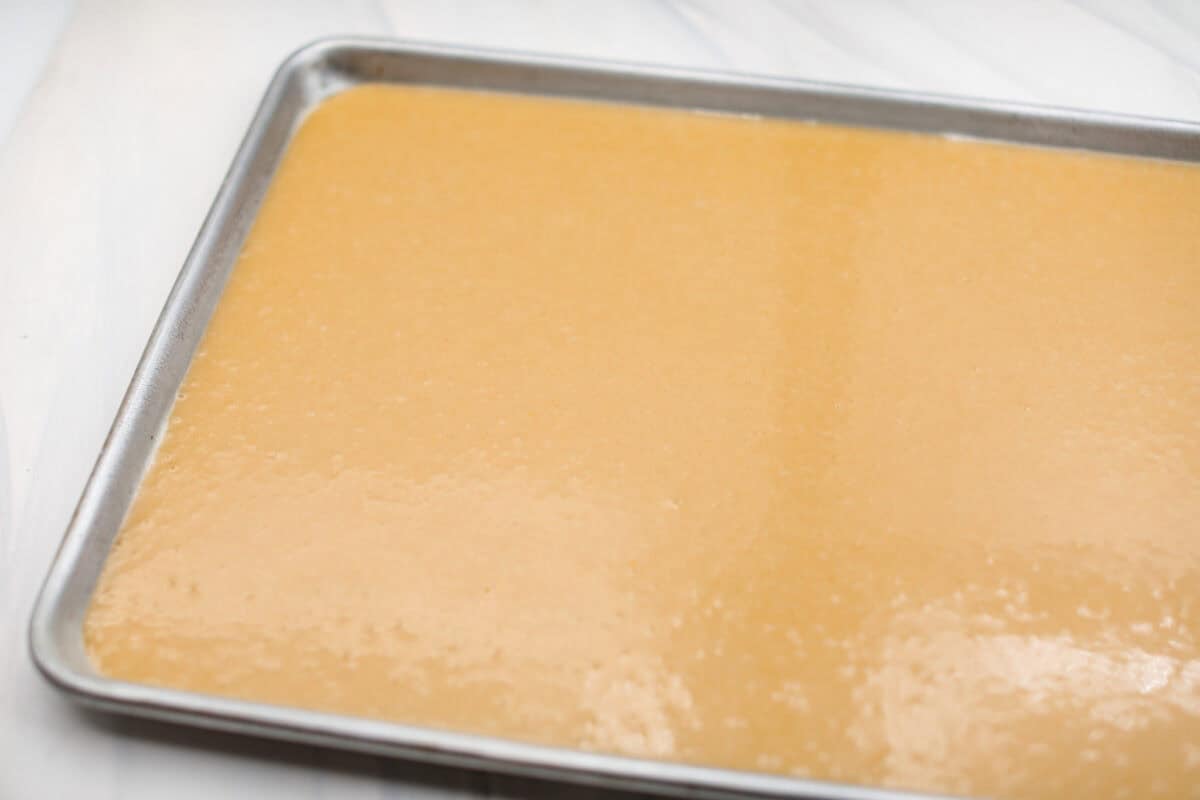 Angle shot of the cake batter spread evenly in the baking sheet. 