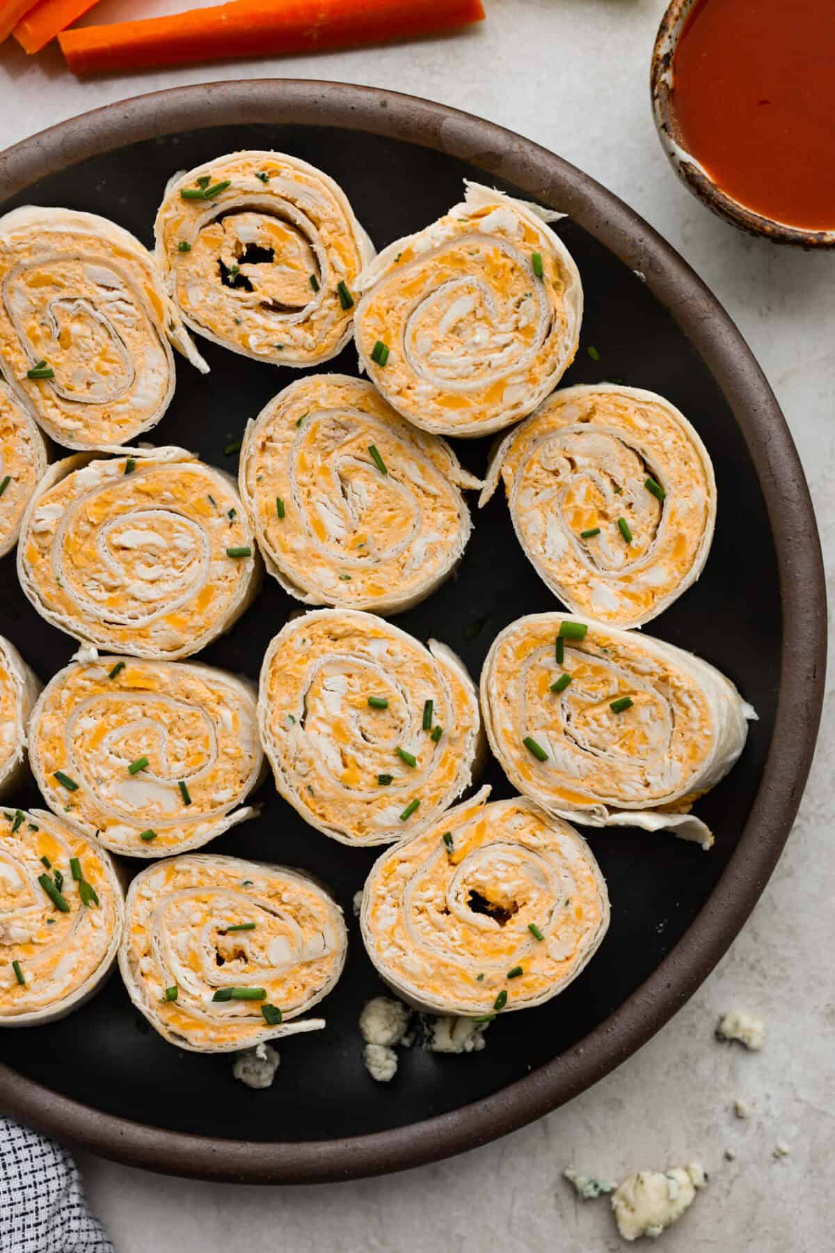 Top view of buffalo chicken pinwheels on a black plate.