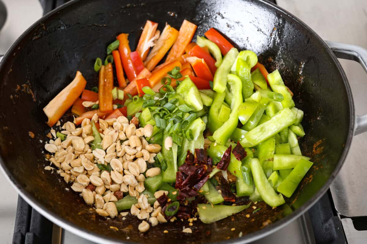 Angle shot of veggies peanuts and dried chilies in the wok. 