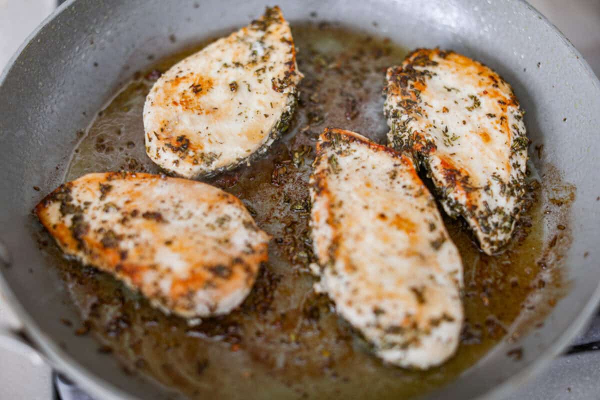 Close up shot of chicken breasts searing on a skillet. 