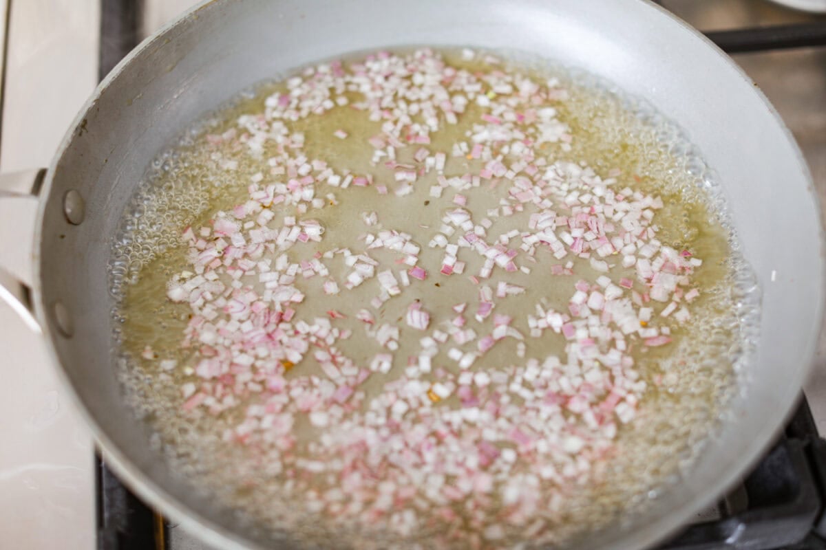 Overhead shot of grape juice and shallots in a saucepan. 