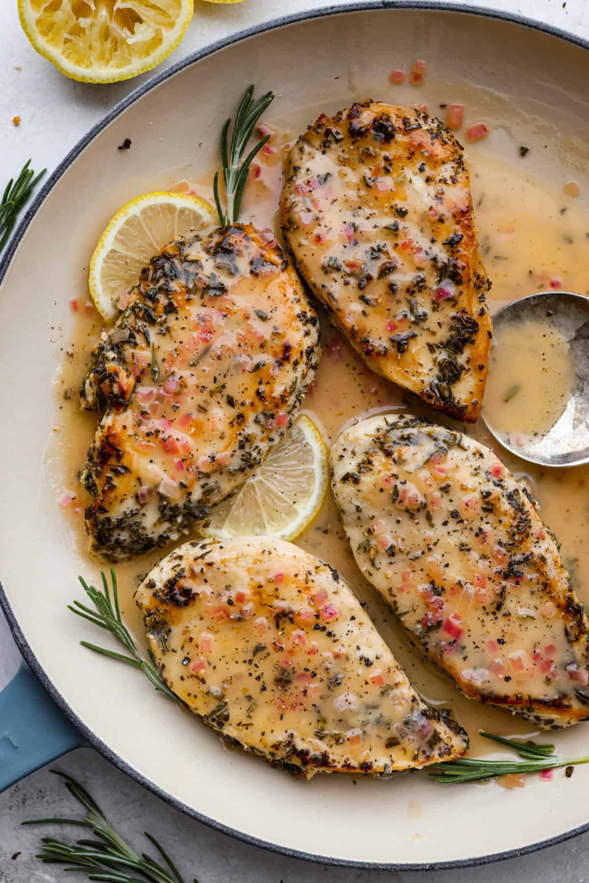 Overhead shot of rosemary chicken on a platter with lemon wedges and sprigs of rosemary. 