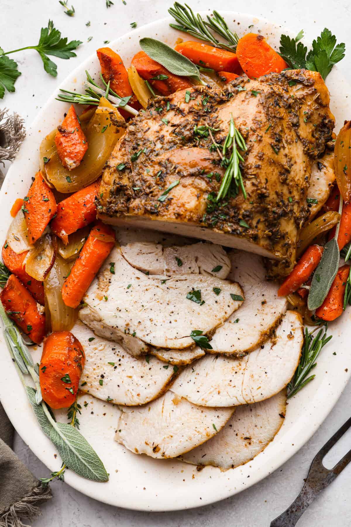 Overhead shot of a platter with the vegetables and slow cooker turkey breast with fresh herbs. 