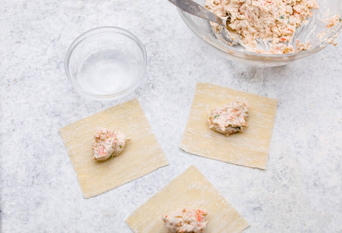 Overhead shot of dollops of mixed filling ingredients on wonton paper. 