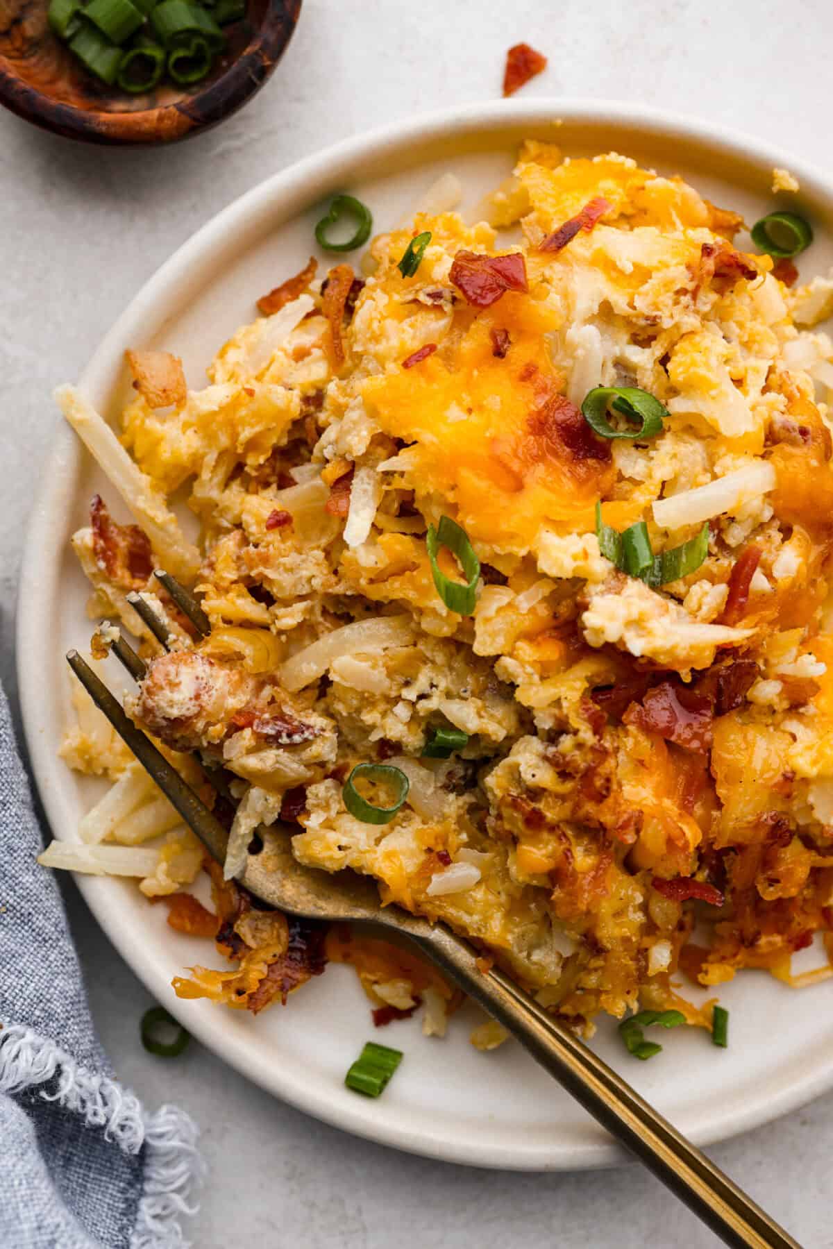 Kickstart your day with this hearty Amish Breakfast Casserole! It's loaded with crispy bacon, tender hash browns, and gooey melted cheese. This dish is a crowd-pleaser that’s perfect for family breakfasts and holiday mornings! Overhead shot of plated amish breakfast casserole.