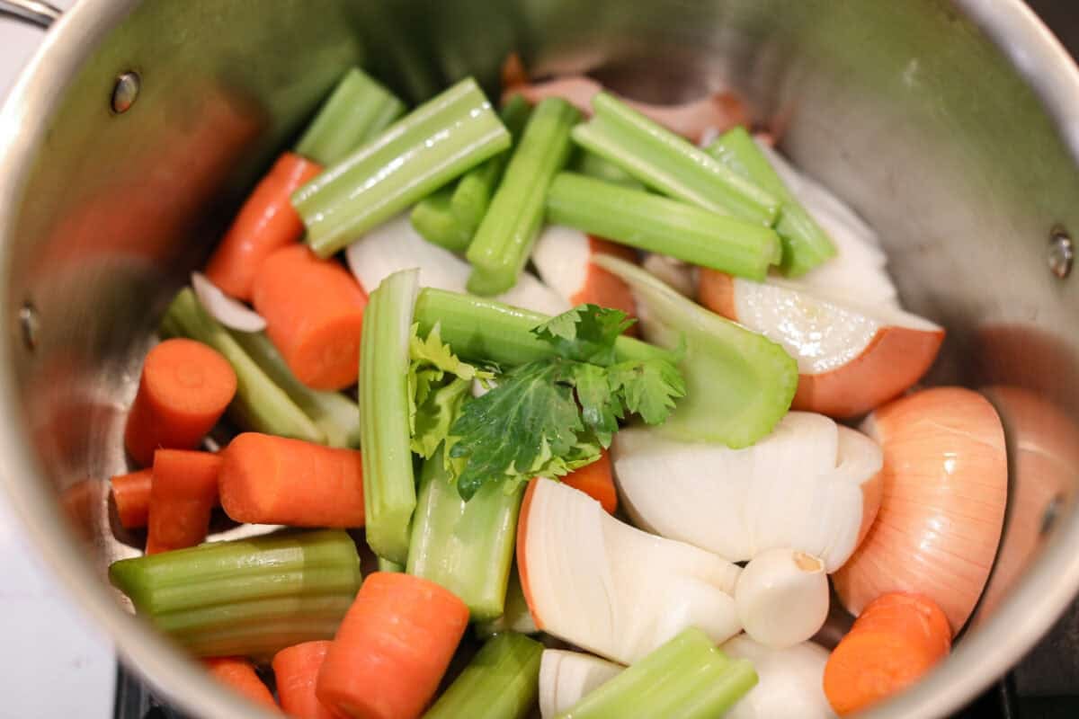 Close up shot of a pile of veggies in a stock pot. 