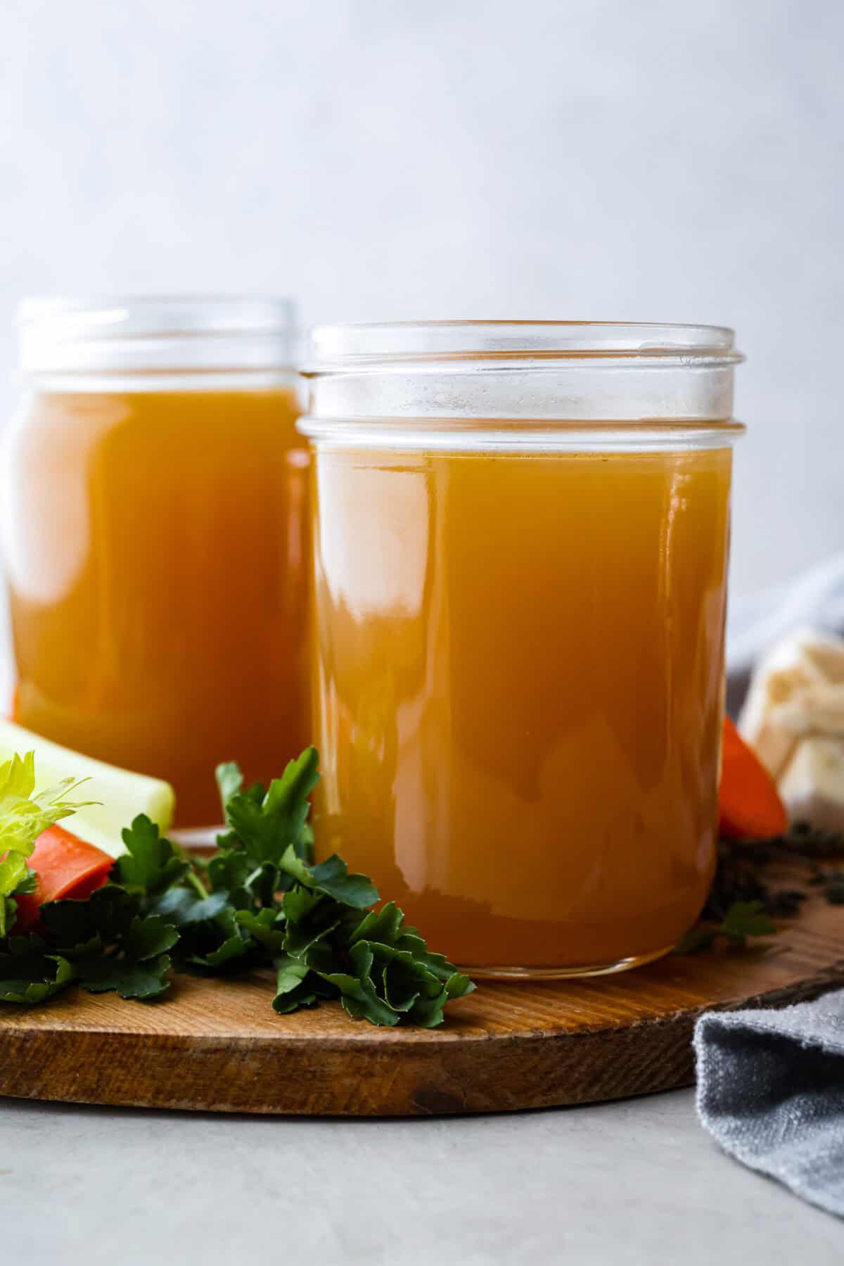 Side shot of two mason jars filled with homemade vegetable broth. 