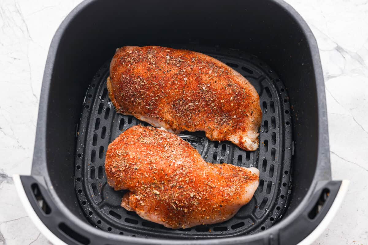 Overhead shot of the seasoned chicken in the air fryer basket. 