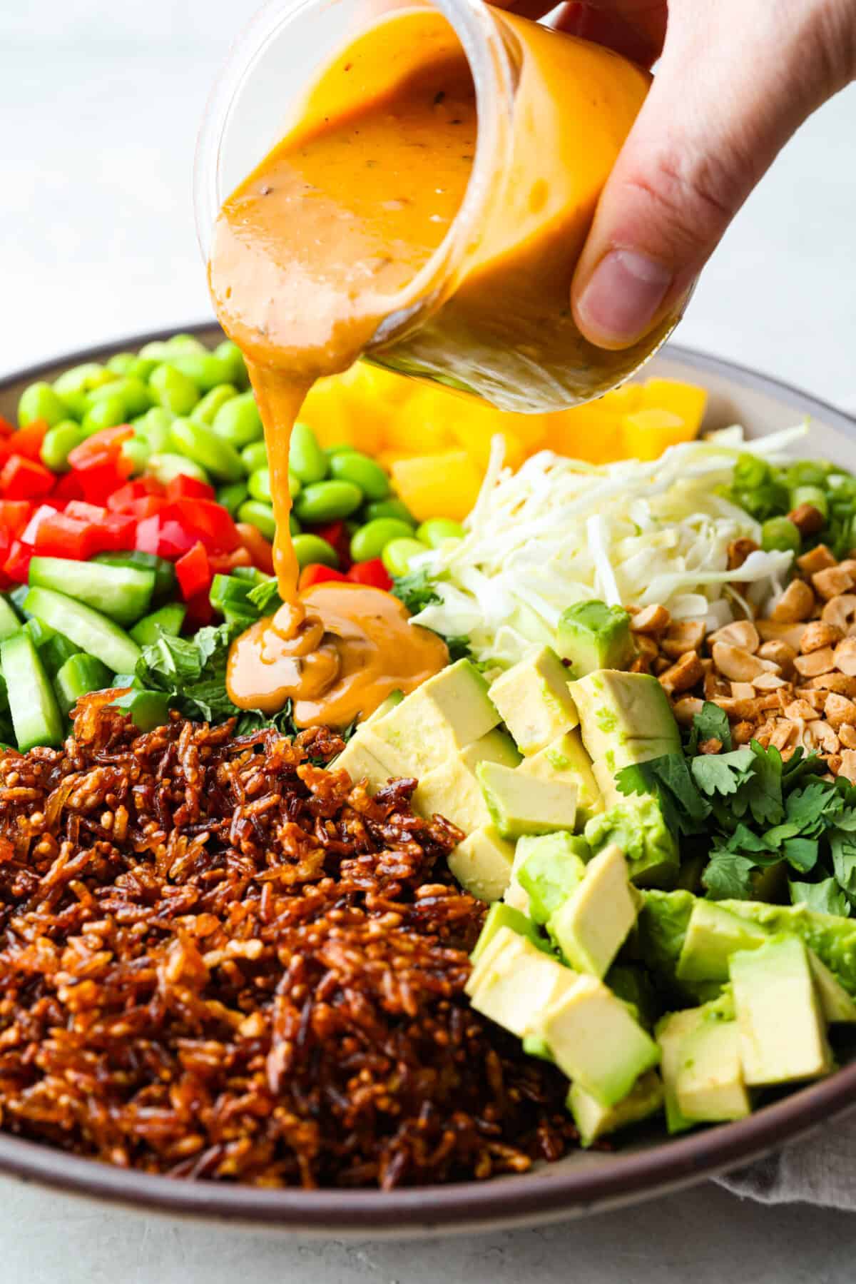 Someone drizzling the dressing over the crispy rice salad.