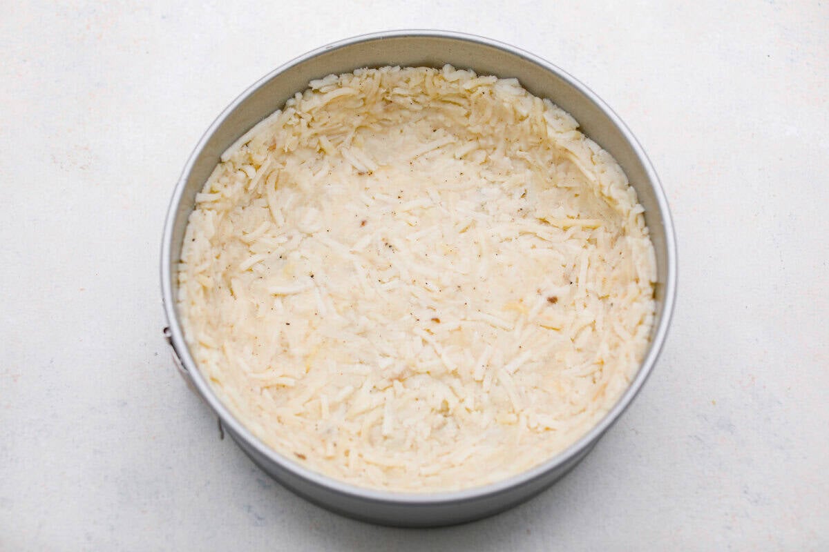 My Hash Brown Crust Quiche is a gluten-free twist on a classic! Crispy, golden potatoes wrap around a rich, savory, custardy filling. Brunch just got an upgrade! Hash brown mixture pressed firmly into the spring form pan.