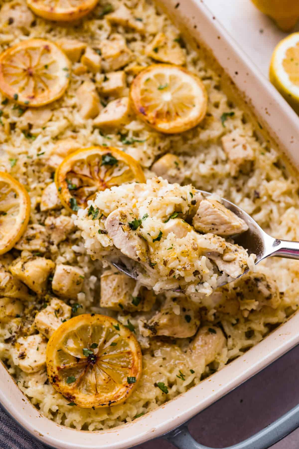 Some on lifting a spoonful of lemon chicken casserole out of the dish.