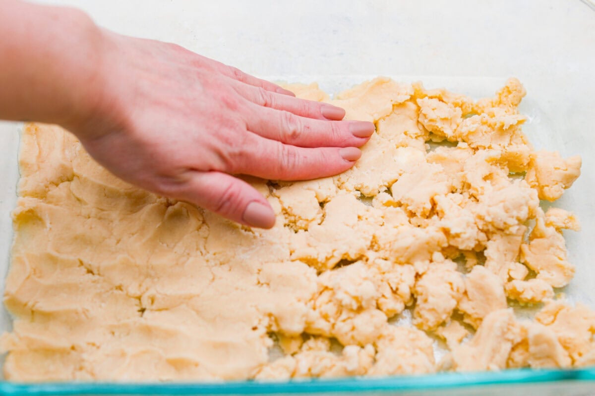 Someone smashing the crust mixture into the bottom of the dish. 